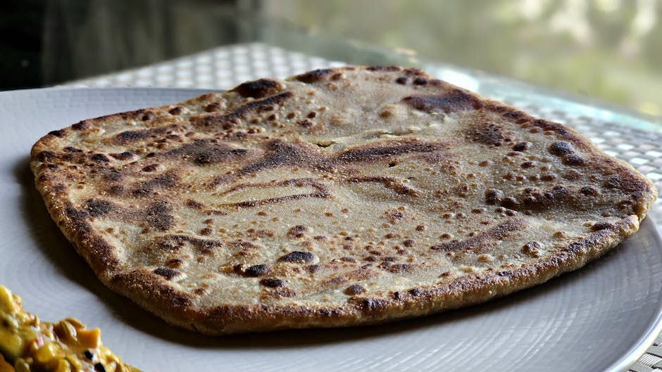 Delicious close-up of a traditional Indian paratha served on a white plate, perfect for culinary themes
