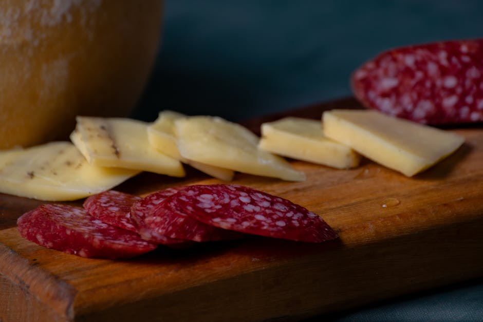 Close-up of sliced cheese and salami on a wooden platter, perfect for appetizers
